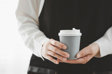 Fototapeta na wymiar closeup woman wearing apron holding paper cup of hot coffee