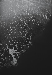 Abstract black and white close-up of sand, water and foam