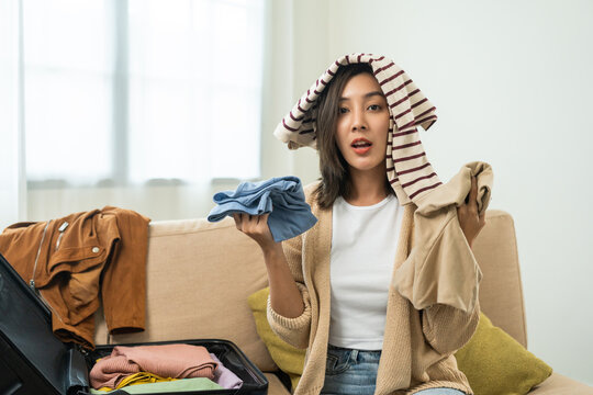 Happy Beautiful Woman To Folding Her Clothes Pack Suitcase For Travel In Holiday. Young Female Folding Clothes While Packing Luggage At Home.