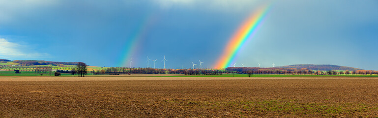 rainbow over a plowed field with village in background, Germany. panoramic view