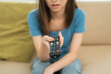 Close up woman hand holding remote control pointing to change the programme television menu.