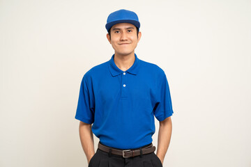 Happy asian man in blue uniform standing on isolated white background. Smiling male delivery service worker. Delivery courier and shipping service.