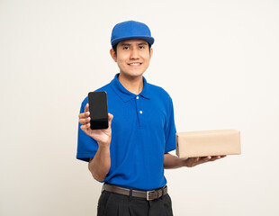 Asian man in blue uniform standing holding box parcel cardboard and smartphone on isolated white background. Male service worker with cell phone. Delivery courier shipping service