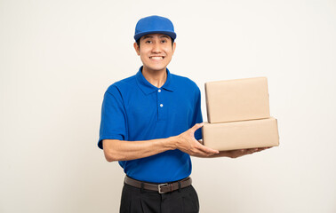 Asian man in blue uniform standing holding box parcel cardboard and smartphone on isolated white background. Male service worker with cell phone. Delivery courier shipping service