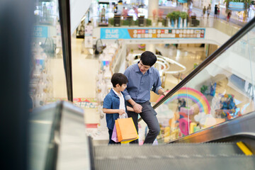Happy cheerful man and little son walking in the supermarket or department store together. Asian man bought a gifts and toys for his son at department store.