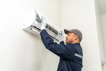 Technician in uniform using tablet to check list of maintenance and cleaning filters of air...