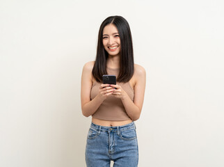 Pretty young asian woman using smartphone standing on isolated white background. Excited Beautiful young asian shopping online payment with mobile phone. Playing game on smartphone