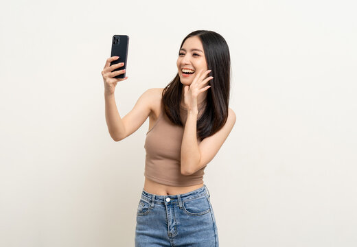 Happy Beautiful young asian woman using smartphone mobile to selfie take photo herself standing on isolated white background.