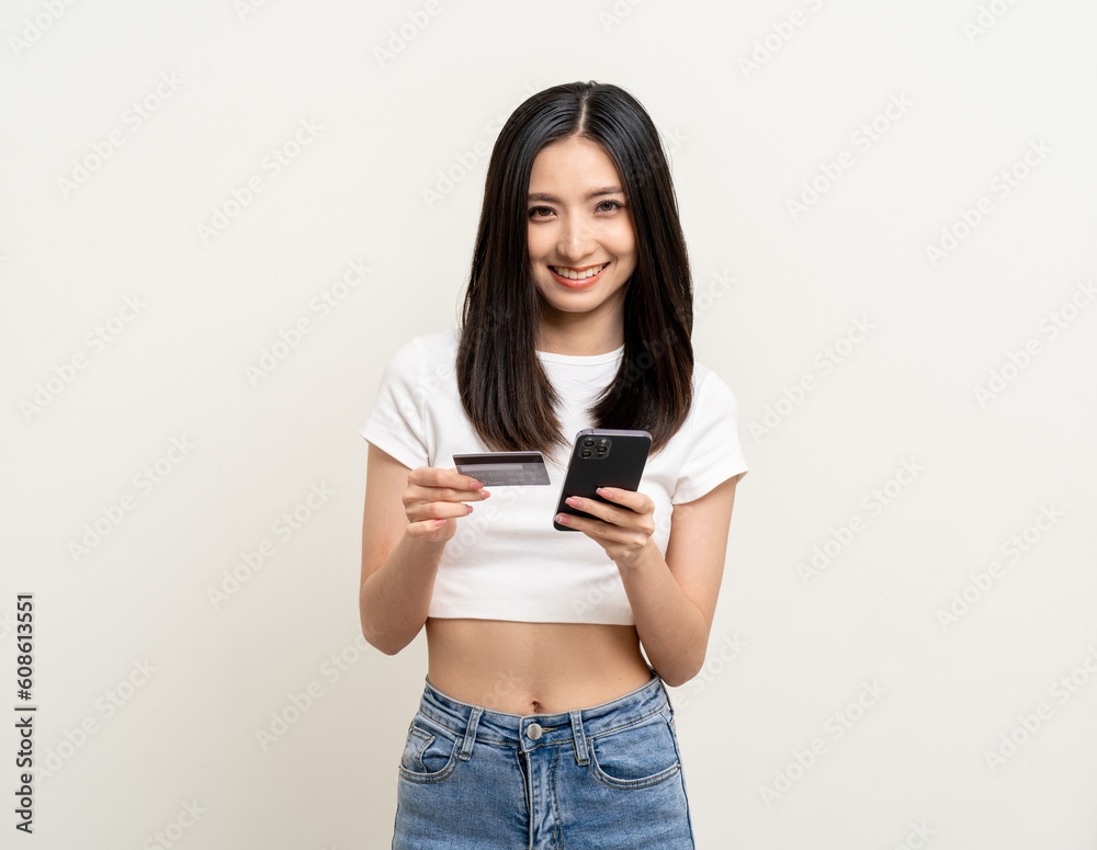 Wall mural Portrait beautiful asian women standing pose holding credit card and smartphone to shopping payment. Attractive Happy businesswoman input the serial number of credit card cell phone financial