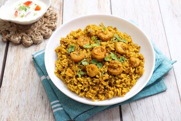 Prawns Biryani or shrimp Pulao. also called jheenga pilaf or jhinga biryani in India. known as Kolambi bhat in Marathi. Garnished with mint leaves, and coriander along with yogurt Raita. Copy space