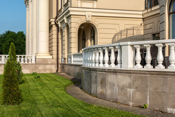 White balustrade on the background of the facade of the building. Lawn with thujas. Vintage place...