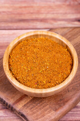Cajun spice powder on wooden background. Powdered dried cajun in wooden bowl