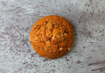 Top view of a cinnamon muffin top on a gray mottled tabletop.