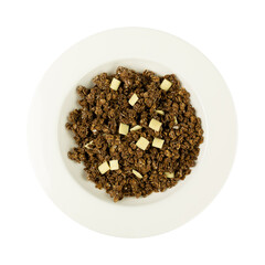 Overhead view of a serving of sweet chocolate granola with pieces of white chocolate in a bowl isolated on a white background.