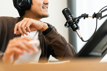 Young asian man host streaming podcast with condenser microphone work on tablet at small broadcast home studio. Content creator blogger recording voice over radio interview guest conversation