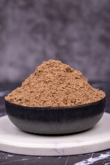 Allspice powder spice on dark background. Powdered dried allspice in bowl. Pimento spice, Jamaican pepper and shavings