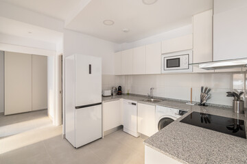 White stylish kitchen with modern appliances refrigerator washing machine and stove for cooking. Concept of a comfortable multifunctional kitchen after renovation