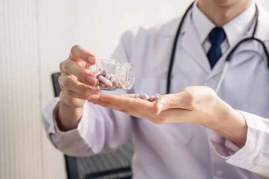 Picture of doctor hands pours out medicine, capsule or pill into her hand. Healthcare and medical concept.