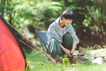 ソロキャンプをしている若い日本人女性/食事の準備