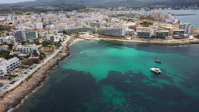 Aerial drone footage of the town of Sant Antoni de Portmany on the west coast of Ibiza Spain&rsquo;s Balearic Islands, showing the ocean front and Cal&oacute; des Moro beach with boats in the ocean