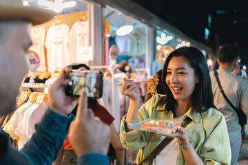 Asian woman enjoy eating noodles street food at night market. Traveler Asian blogger women Happy tourists Beautiful female with Traditional thailand bangkok food.