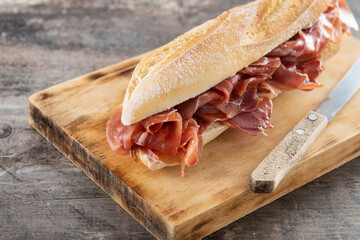 Spanish serrano ham sandwich on wooden table - obrazy, fototapety, plakaty