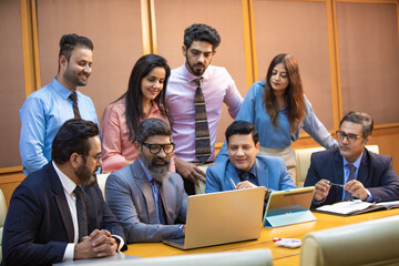 Indian businessman showing some detail in laptop to his partner and employee at office.