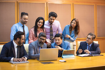 Indian businessman showing some detail in laptop to his partner and employee at office. © Niks Ads