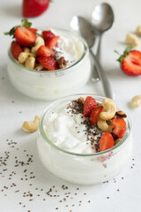 Glass jar of Greek yogurt, nuts and strawberries on a tray close up, copy space