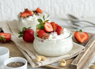 Glass jars of Greek yogurt, nuts and strawberries on a tray close up, copy space