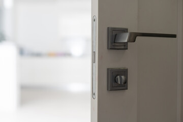Chrome handle with keyhole on white door with panels in frames. Entrance. Close-up photo of architecture detail. Interior fragment as geometrical background with three rectangles and parallel lines