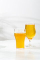 Two pint glass light beer on white table copy space