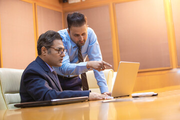 Obraz premium Young Indian manager showing project detail in laptop and discussing with his boss or senior.