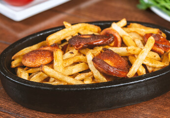Frying pan with pieces fried sausage and potato