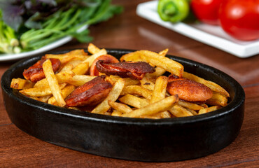 Frying pan with pieces fried sausage and potato