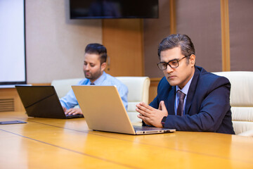 Indian businessman giving unhappy expression after looking in laptop at office.