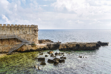 A man over the rocks at the Ionian Sea in Sicily  
