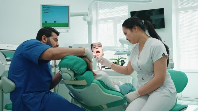Smiling asian dentist woman examining patient oral cavity in hospital. Doctor appointment