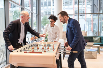 Business people play table football at the foosball table