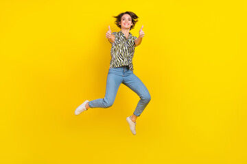 Fototapeta na wymiar Full length photo of pretty confident woman dressed zebra striped shirt jumping high showing thumbs up isolated yellow color background