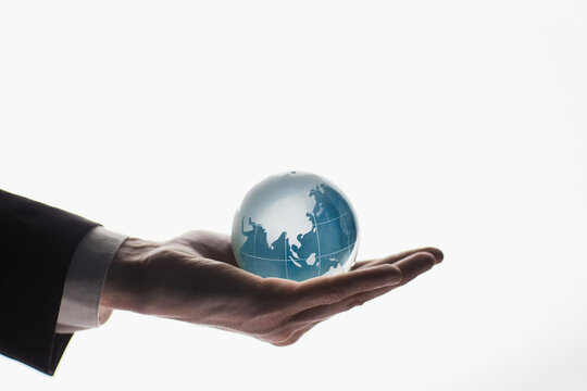 Businessman holding glass globe isolated on white background - Powered by Adobe