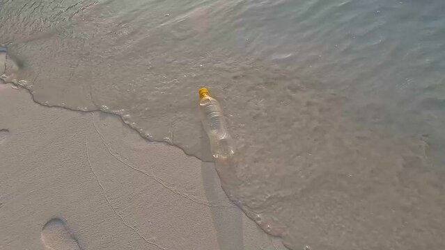 The plastic bottle floating in the sea  with dirty coast on the beach 