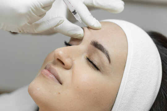 Injection with a syringe with butolin on a woman's face. Care with love: a woman visits a beautician for botulinum therapy, which makes her skin soft, smooth and youthful. Beauty clinic