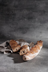 French baguette on a cotton towel on a grey background close-up. Free space for text