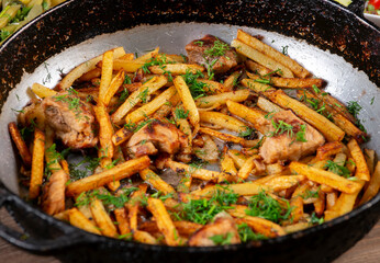 Fried Meat with fried halves of potatoes in a skillet