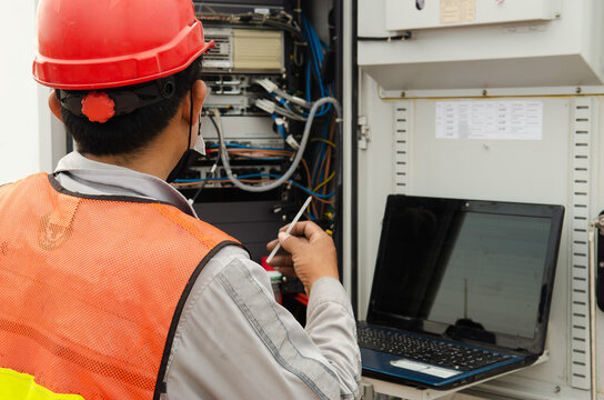 Engineer or Technician wear safety equipment working with control panel of telecom tower, high risk work, technology conceptual ,tech use laptop or tablet for inspect ,maintenance ,commissioning work