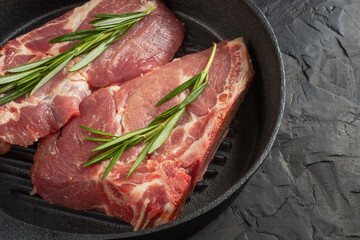 fresh delicious juicy meat steaks delicacy on a black pan with rosemary and spices on a black table with free space for text