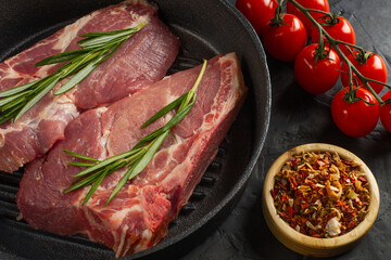fresh delicious juicy meat steaks delicacy on a black pan with rosemary and spices on a black table with free space for text