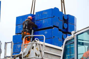 Worker in hi-vis and hard hat guides heavy steel counterweight into place on 1000 ton mobile crane