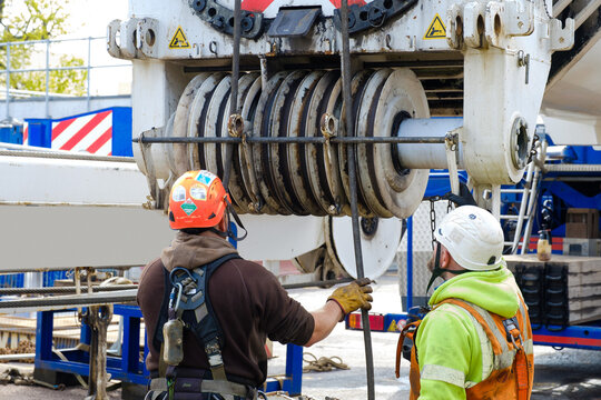 workers in hi-vis and hard hats inspect heavy mobile crane winding gear